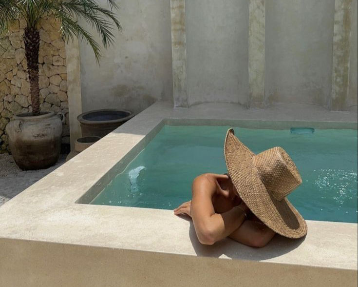 woman with large hat in luxury pool