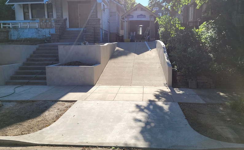 concrete retaining wall, staircase, and driveway leading up to residential home 