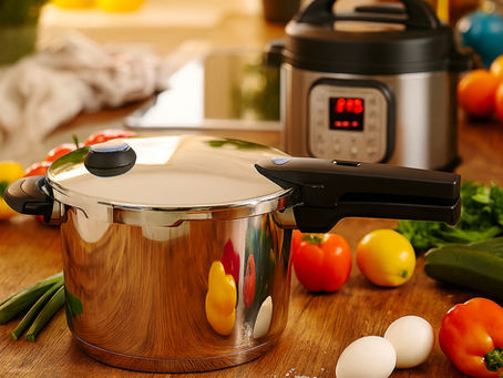 Ein Schnellkochtopf ohne Schadstoffe aus Edelstahl steht auf einer Küchenarbeitsplatte, dahinter ein Multikocher – beide umgeben von frischen Zutaten wie Eiern und Gemüse. Ideal für gesundes, nachhaltiges Kochen im Alltag.