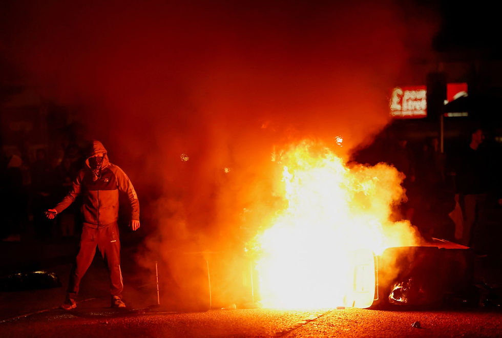 Fire burns near a masked demonstrator as riots continue in Ballymena, Northern Ireland, June 11, 2025. REUTERS/Clodagh Kilcoyne/File Photo