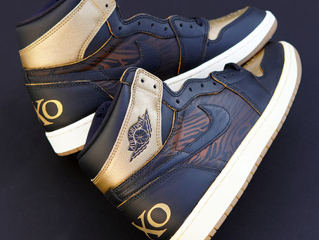 Custom black and gold Air Jordan 1 Retro sneakers inspired by 2XO Whiskey's Sneakerhead Blend, showcasing woodgrain artwork, premium finishes, and custom 2XO heel branding.