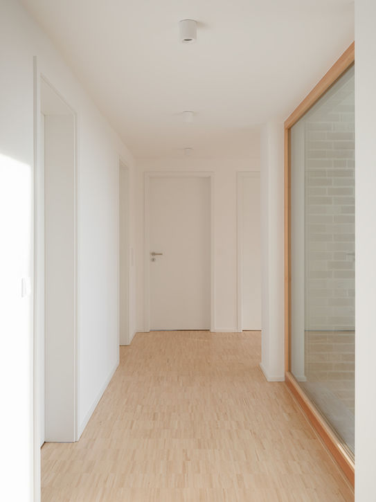 Upper floor hallway in private residence Aachen — minimalist interior with large window and white surfaces