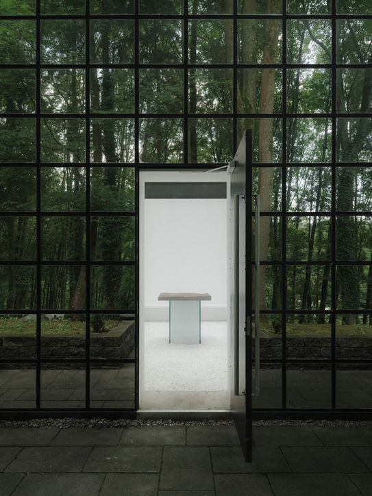 Open entrance of columbarium — contrast between dark forest exterior and bright white interior space