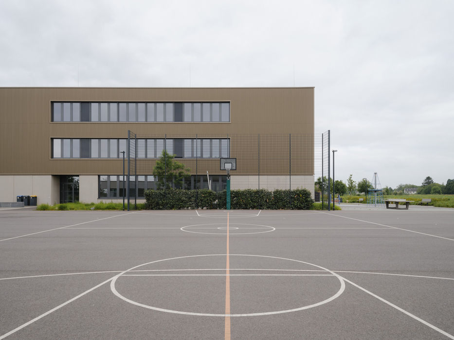 Outdoor sports area at Gymnasium Zusestraße, Cologne — basketball court with school architecture in background
