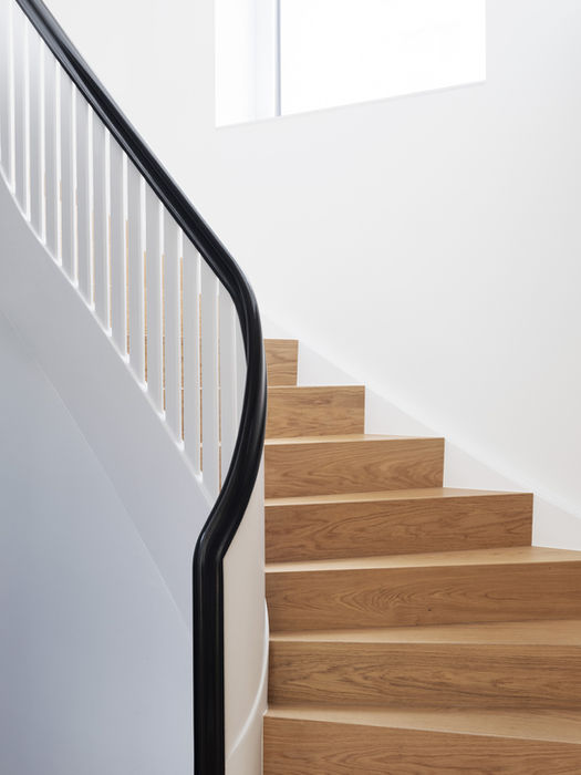 Interior detail of spiral staircase in private residence, Berlin — wooden steps, white structure and black handrail
