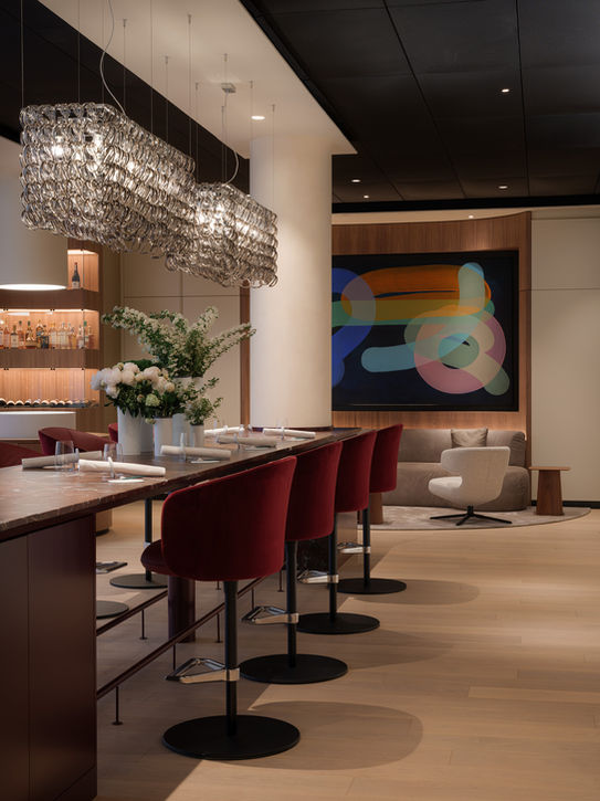 Detail of central bar La Vie Dusseldorf — red counter, seating and decorative ceiling lighting