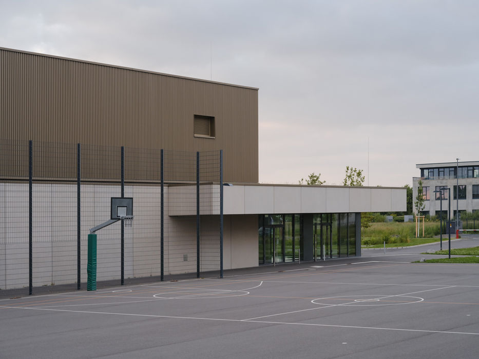 Sports field at Gymnasium Zusestraße, Cologne — evening light with school building and goal structure
