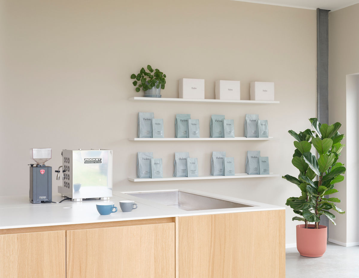 Coffee display in Cafeschule Holm, Potsdam — shelving with coffee bags, cups and branded packaging