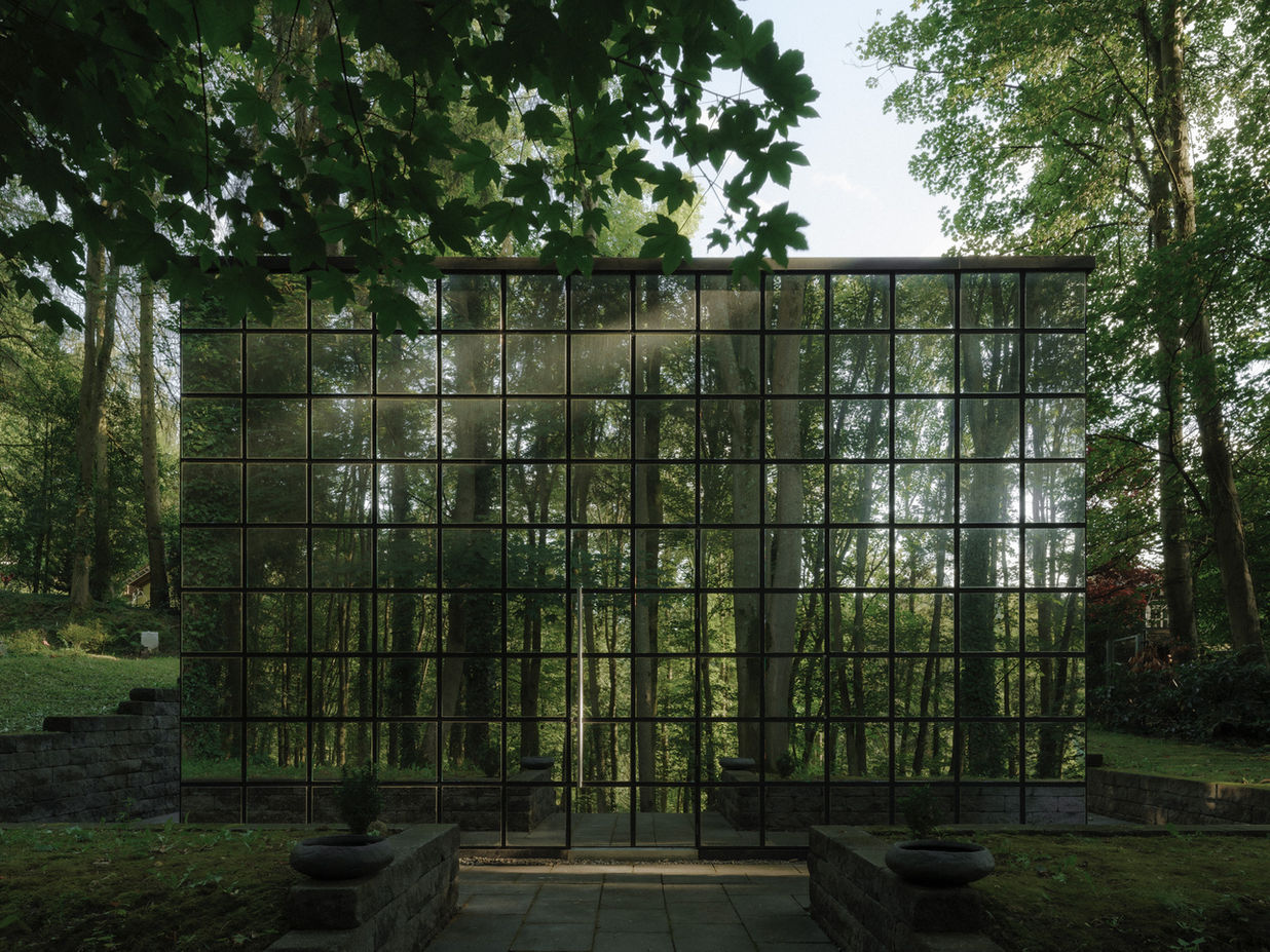 Closed exterior view of Haus der Klage — reflective cube blending into forest surroundings