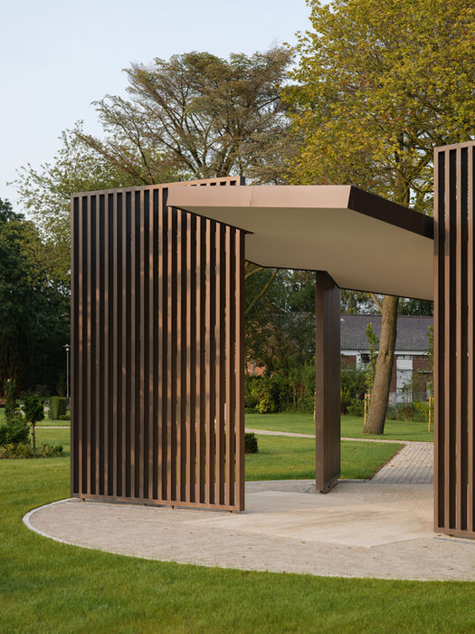 Exterior view of cemetery pavilion — three steel beams and brick wall structure in natural landscape