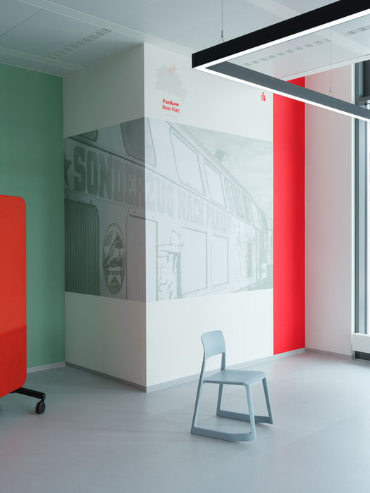 Interior of Sparkasse headquarters Berlin — seating area with blue chair, red acoustic wall and conceptual city artwork