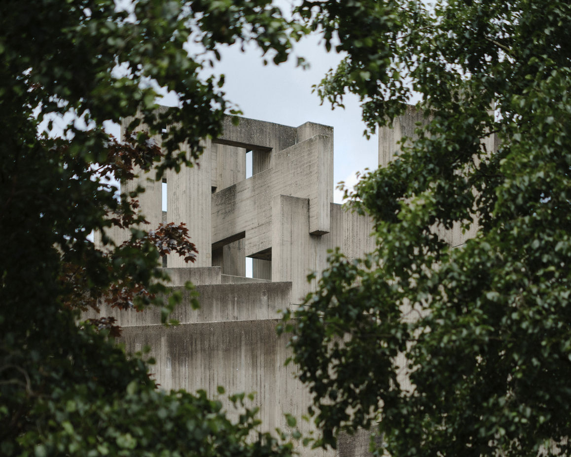 Church exterior framed by trees — brutalist concrete structure seen through natural foreground elements