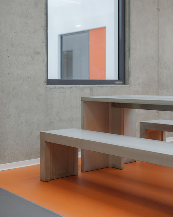 Detail of school interior furniture — concrete-style seating with orange and grey flooring elements