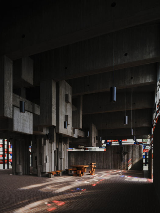 Vertical interior view of brutalist church — concrete structure and filtered light through colored windows