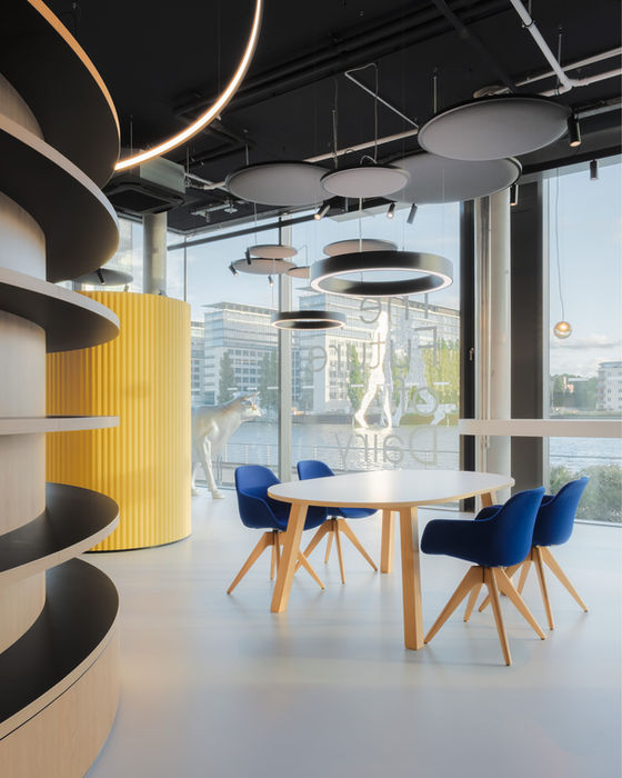 Work and meeting area in Formo offices — wooden table with blue chairs and curved shelving elements