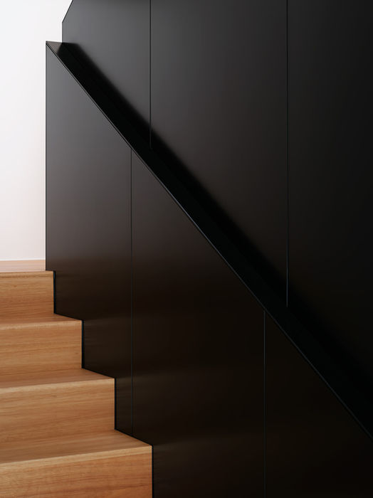 Detail of staircase in private residence Aachen — wooden steps with black railing and structural elements