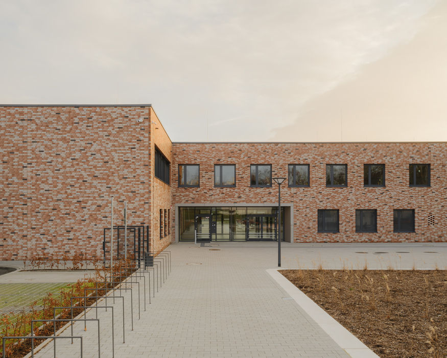 Exterior view of Bildungscampus Unna — brick school building in evening light with geometric facade composition