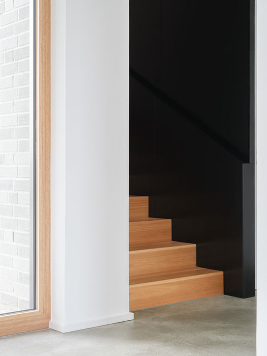 Staircase interior in private residence Aachen — wooden steps, concrete floor and black structural frame