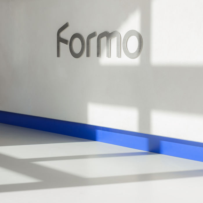 Detail of reception counter in Formo offices — Formo signage with blue base element and natural daylight