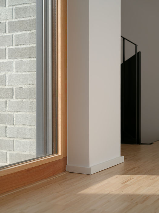 Interior detail of private residence Aachen — wooden floor, window frames and view of exterior brick facade