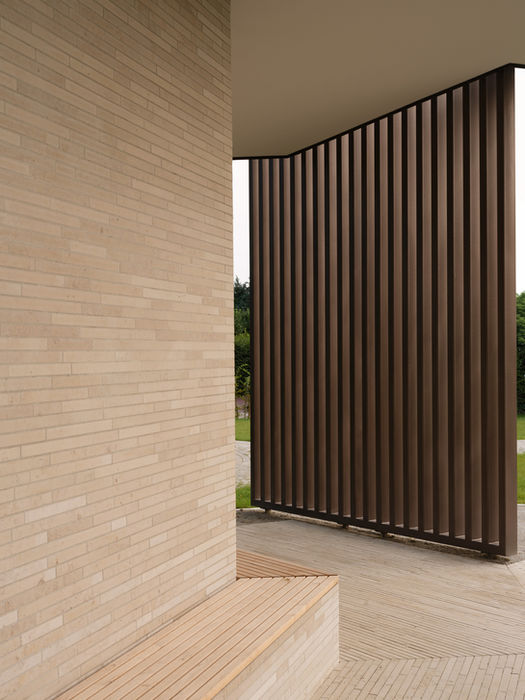 Minimal interior view of cemetery pavilion — steel beams and brick surfaces with soft natural lighting