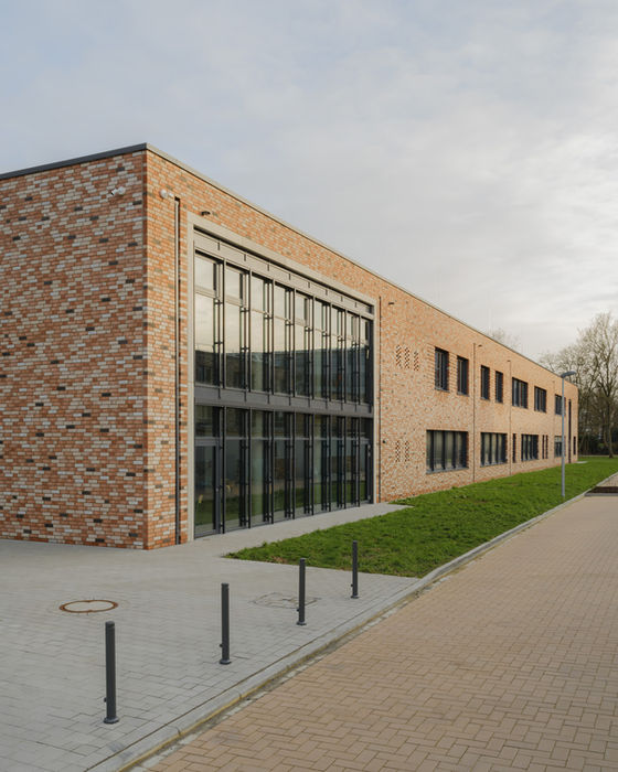 Daytime exterior of Bildungscampus Unna — brick facade with large windows and orange accent details