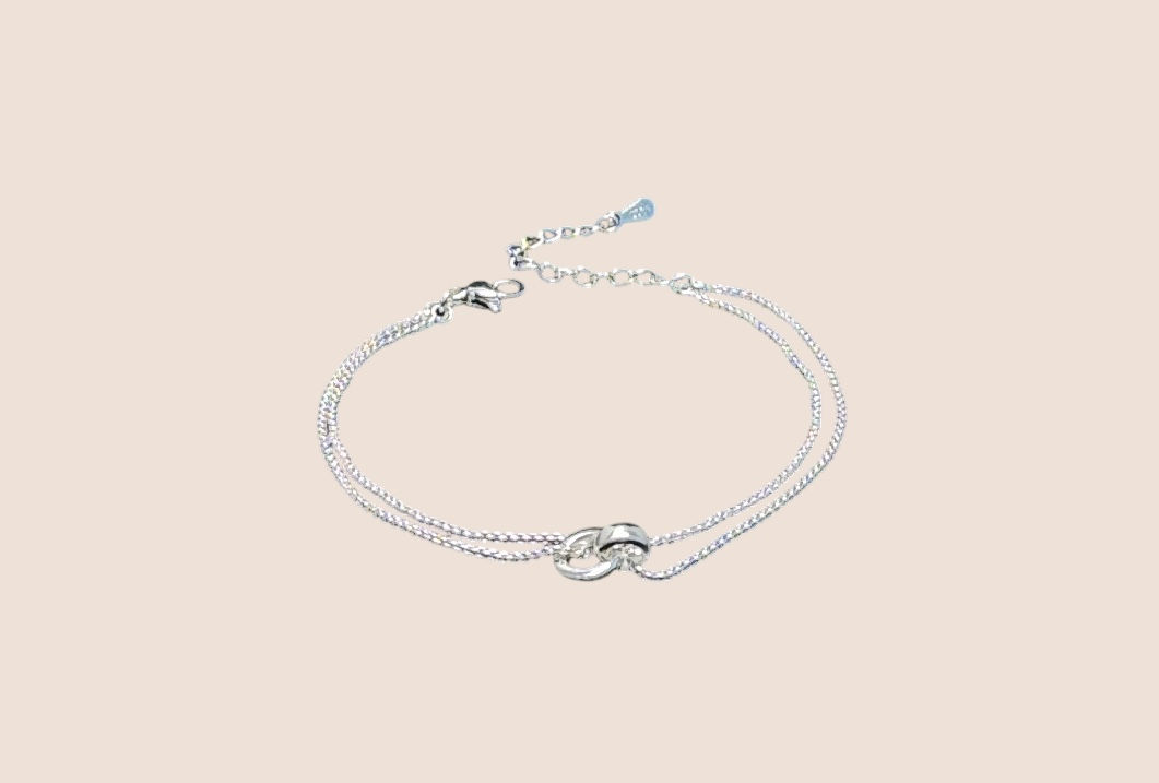 Silver minimalist double chain bracelet with interlocking rings on light background.