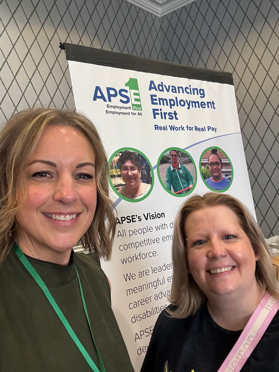 Charly Sullivan and Brooke Murray in front of an APSE sign that says "Advancing Employment First."