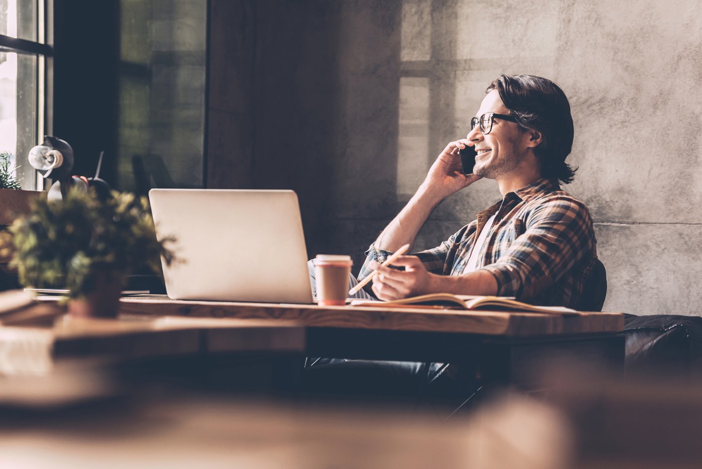 Man talking on the phone beside his laptop