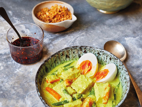 Bowl of vegetarian lontong with coconut broth, boiled egg and chilli oil
