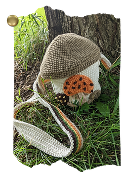 Crocheted purse made to look like a 70s Sears Merry Mushrooms styled container. The purse is sitting in the grass at the base of a tree. The image is styled to look like it has been ripped along the edges, and has a brass tack holding it onto the corkboard background of this page.