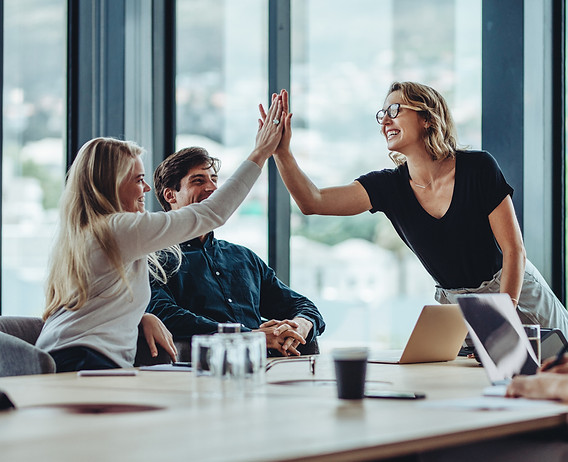 laughing people high-fiving and computers on a table