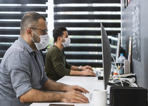 Masked employees at computer desks