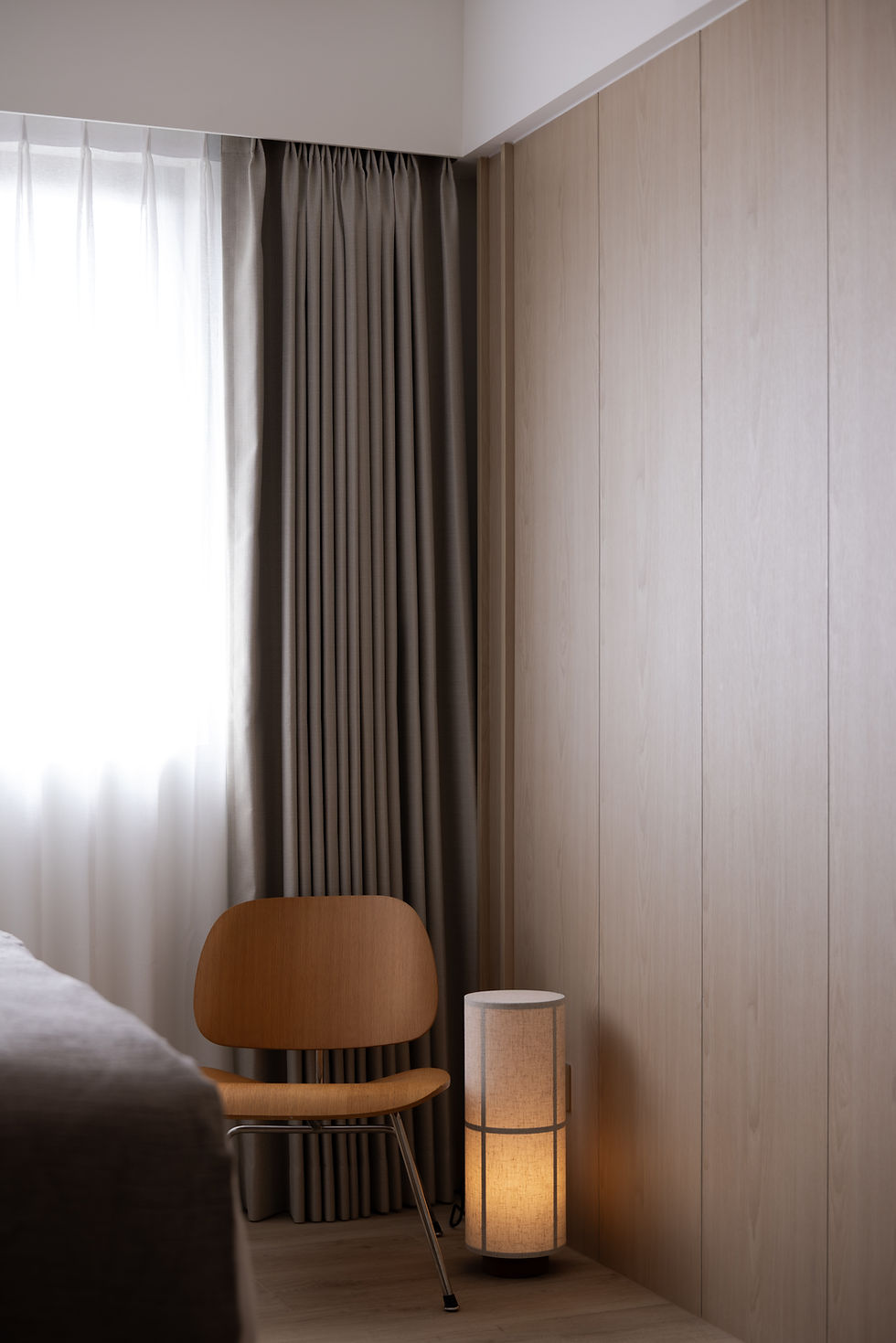 Light-Filled Apartment bedroom corner featuring full-height curtains, integrated wall panelling and softly filtered natural light.