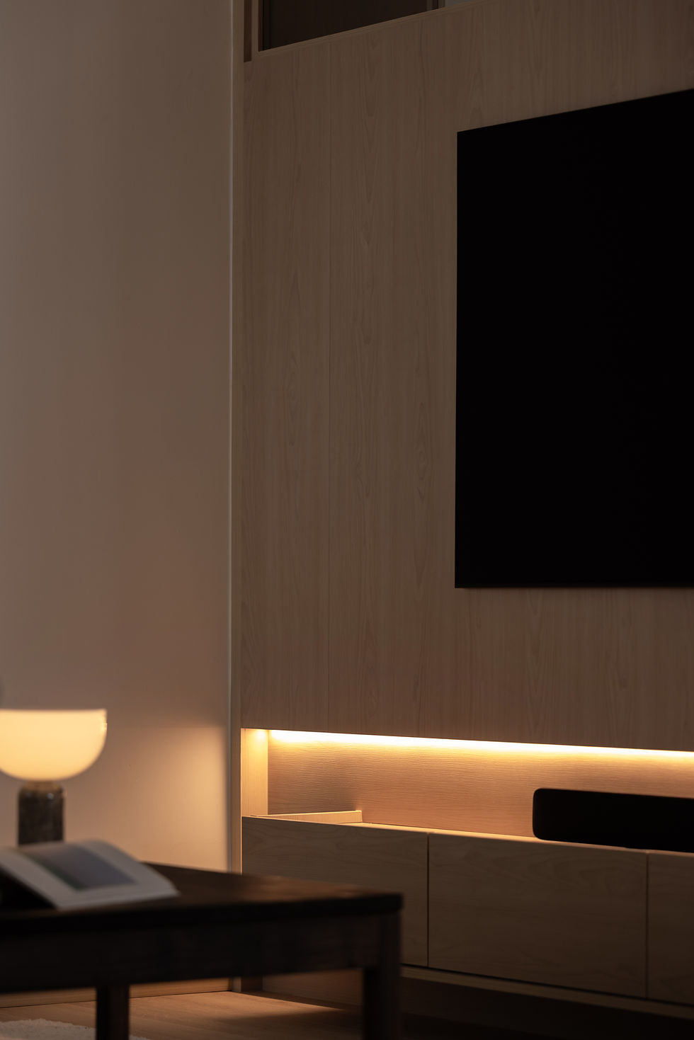 Light-Filled Apartment living room detail featuring a floating television console and softly illuminated joinery.