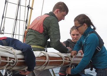 Ordinary Seaman showing trainees the ropes, literally. Summer camp.