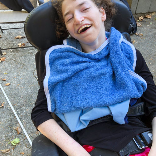 Person smiling outside in a wheelchair.