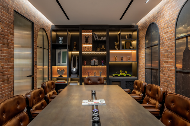 Industrial-style meeting room with brick walls, leather chairs and illuminated display shelving.
