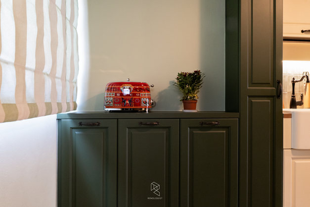 Cozy English Cottage Farmhouse kitchen styling featuring deep green shaker cabinetry, open countertop display, SMEG toaster, warm wood countertop, and vintage-inspired accessories.