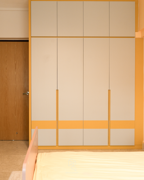 Modern Contemporary bedroom wardrobe featuring full-height built-in cabinetry, overhead storage, recessed vertical handles, and a warm cream and mustard yellow colour scheme.