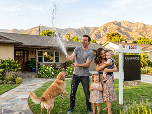 a young family celebrating the purchase of their new home with champagne spraying from a bottle in the front yard of their new home in Tarzana