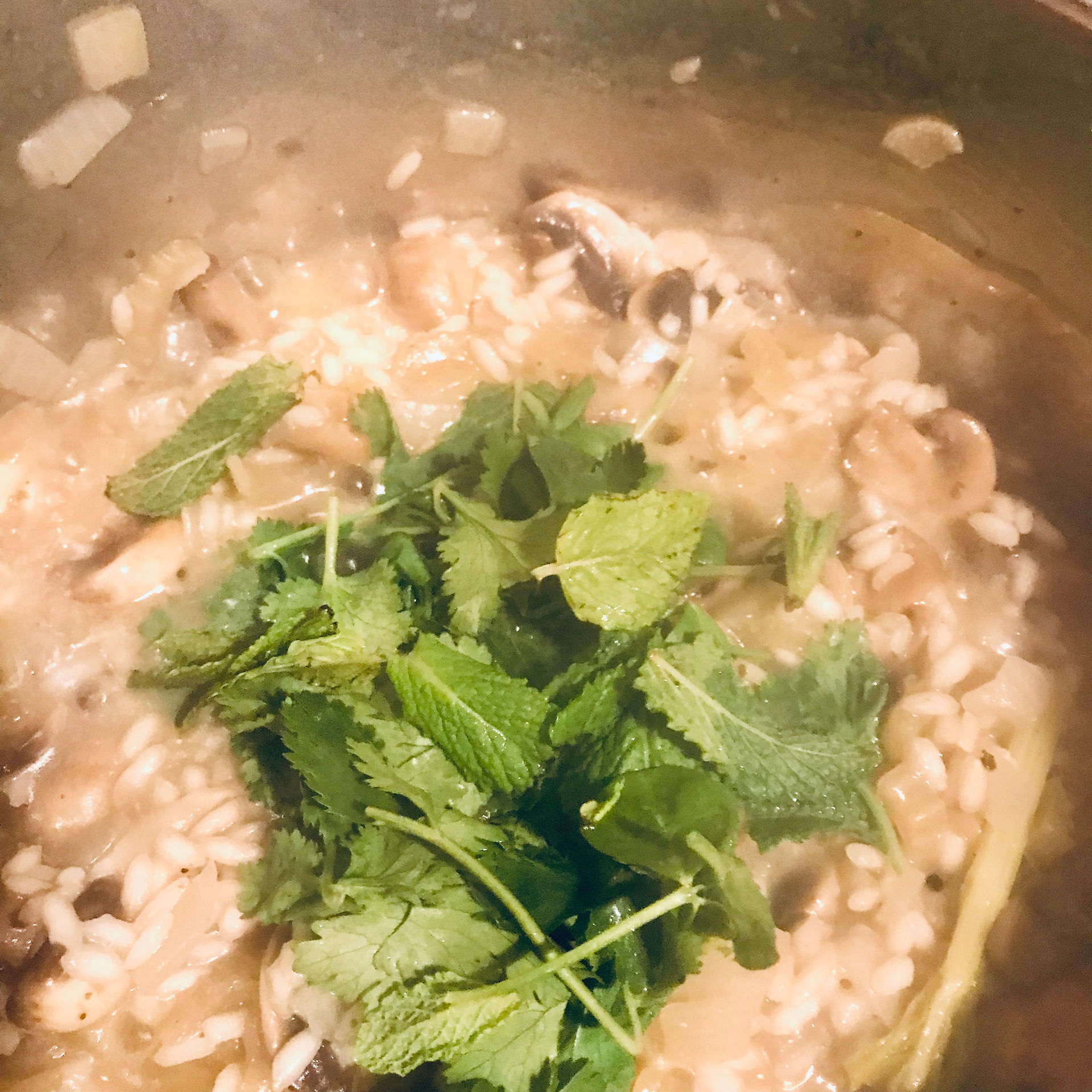 Add half of the fresh herbs to the top of the cooking risotto