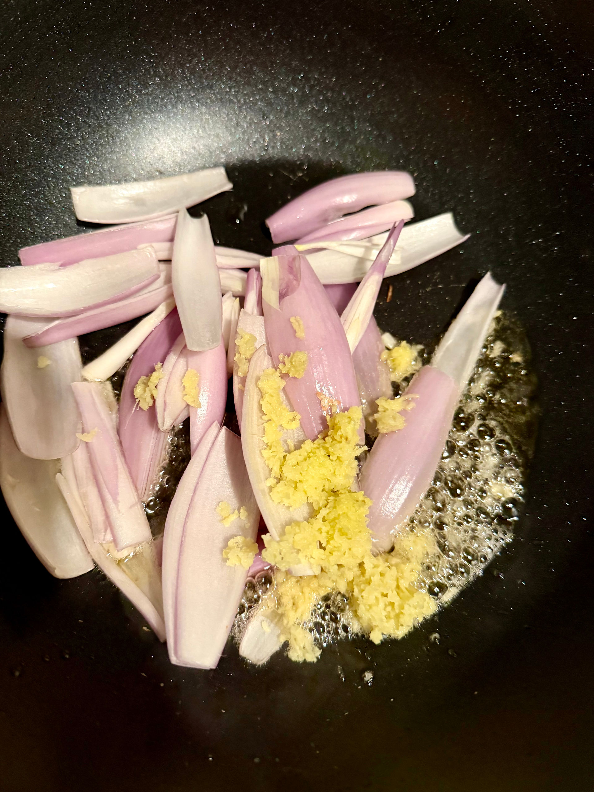 Add the shallots to the wok, followed by the ginger and garlic