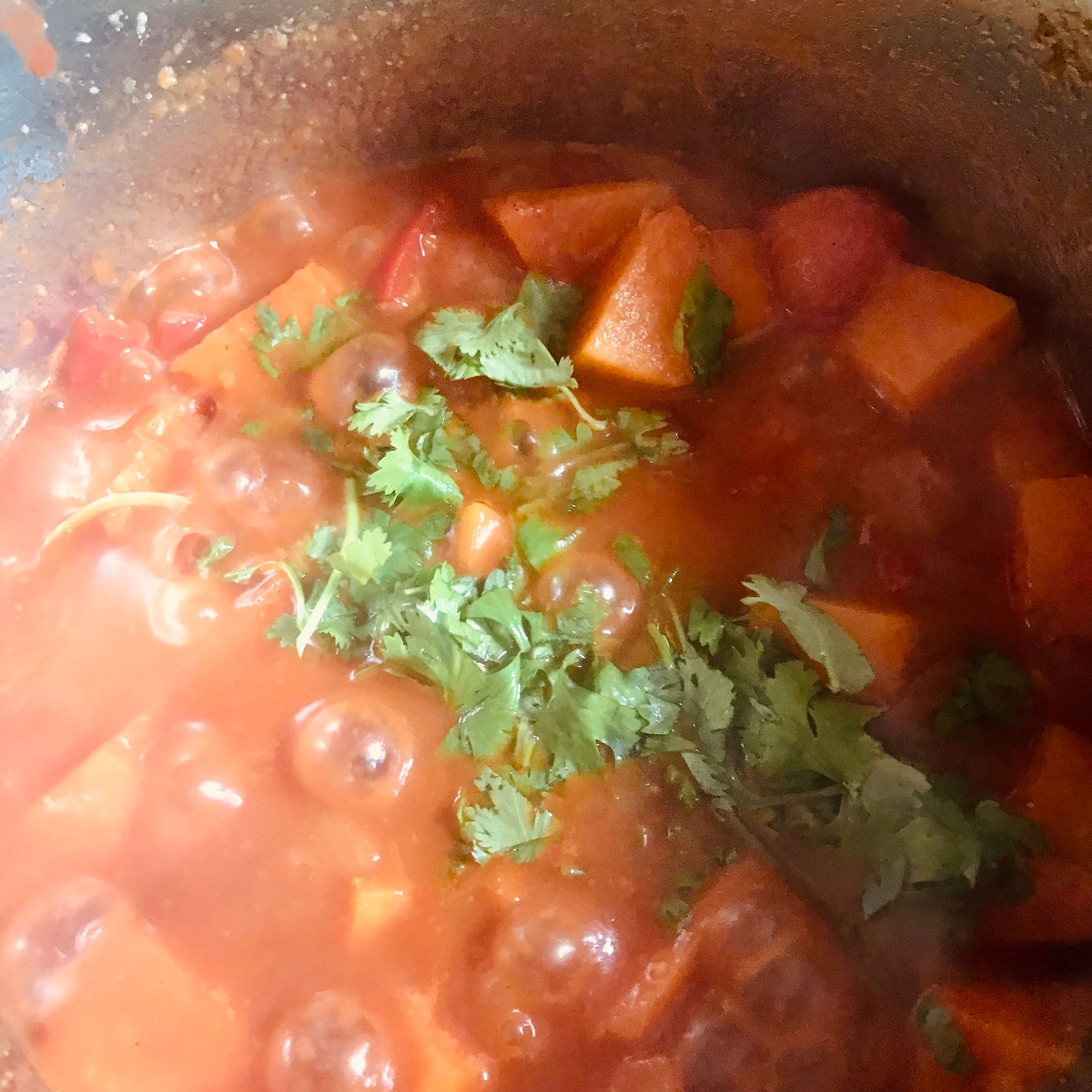 Add the chopped fresh coriander to the top of the reducing curry sauce