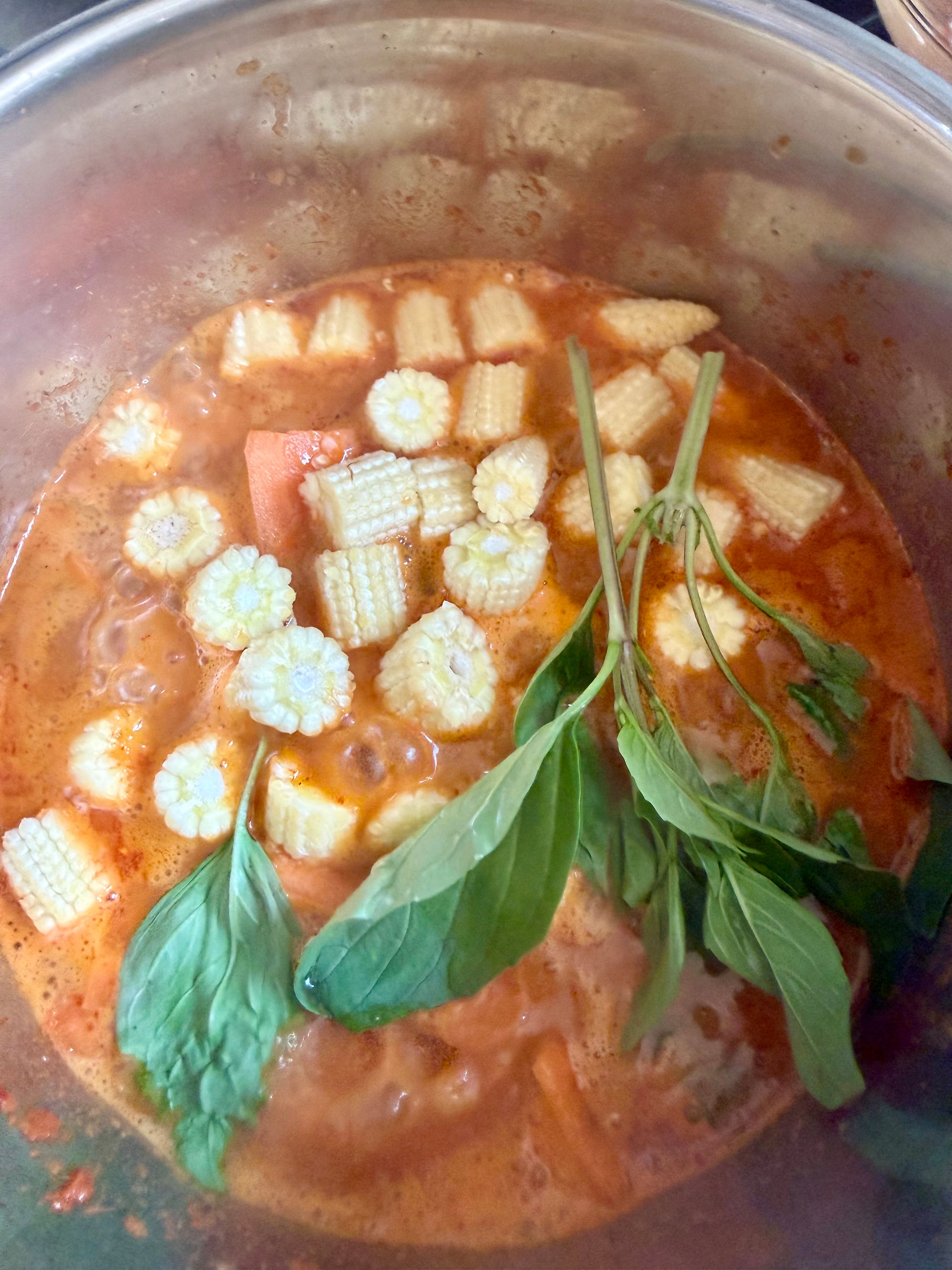 Add the sweetcorn to the coconut milk and top with Thai basil