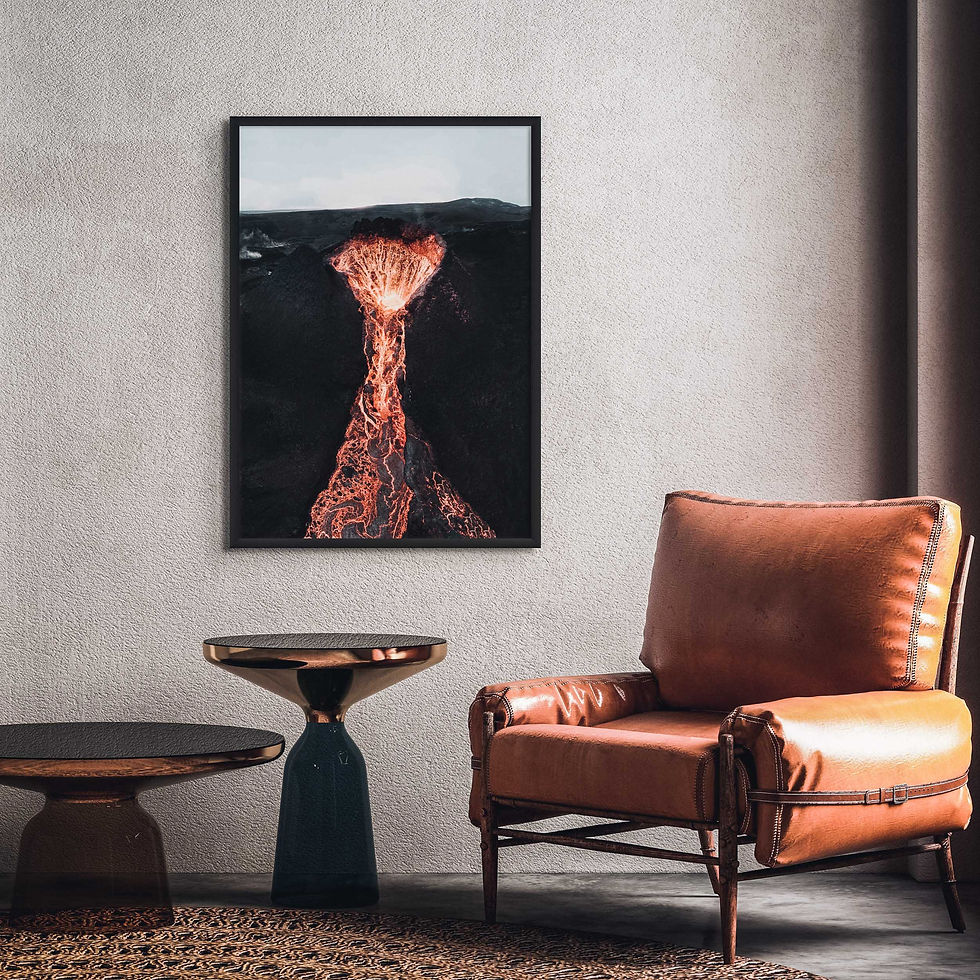 Thumbnail: Black framed print of an active volcano crater, with flowing lava, hung above an armchair