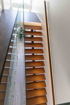 The glass balustrade wraps from the staircase onto the second story of this modern Auckland home.