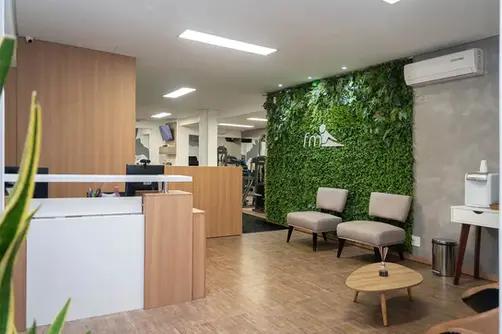 Recepção da FM Campo Belo, com poltronas, balção e jardim vertical com a marca da clínica na parede.