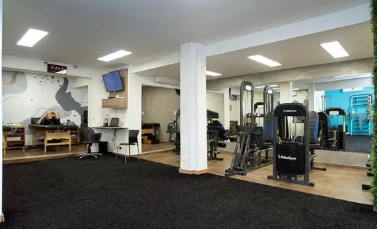Salas com equipamentos de musculação, macas e gramado para treino funcional.
