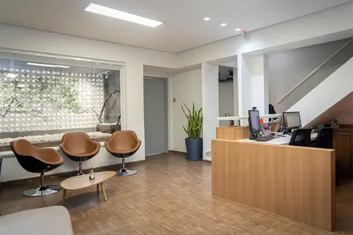 Ambiente de tratamento, com piso de grama sintética, com macas e equipamentos de musculação.